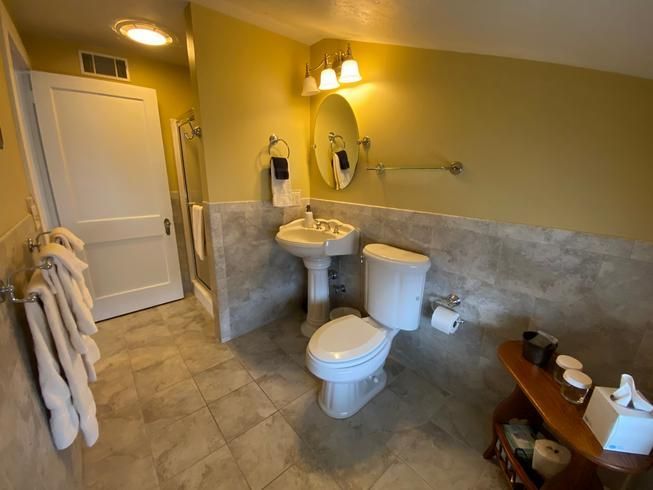 A bathroom with a toilet , sink and mirror.