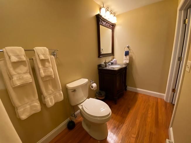 A bathroom with a toilet , sink and mirror.