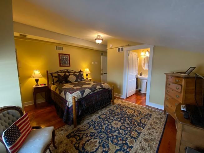 A bedroom with a bed , dresser , chair and rug.