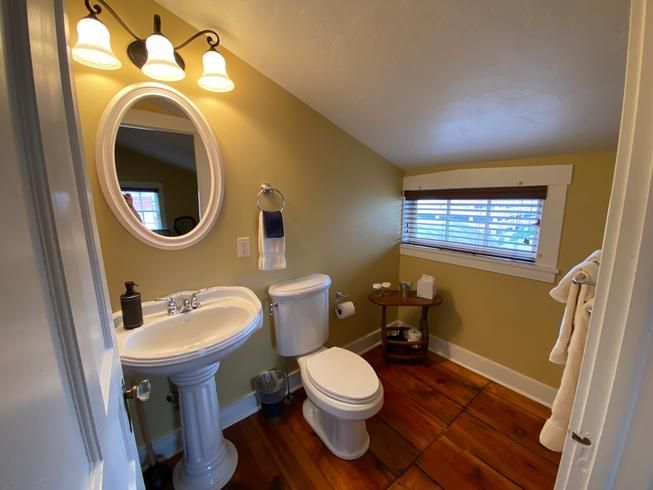 A bathroom with a sink , toilet , mirror and window.