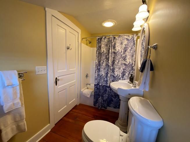 A bathroom with a toilet a sink and a shower curtain