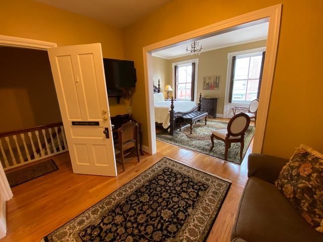 A living room with a couch and a rug leading to a bedroom.