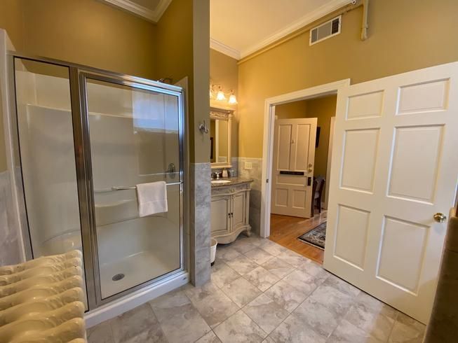 A bathroom with a walk in shower , sink and mirror.