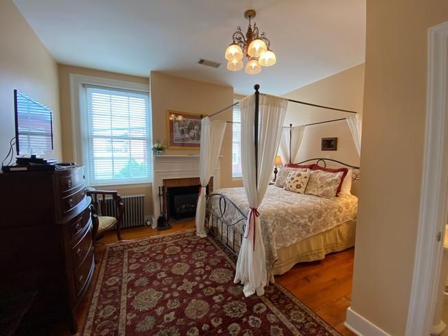 A bedroom with a canopy bed and a fireplace.