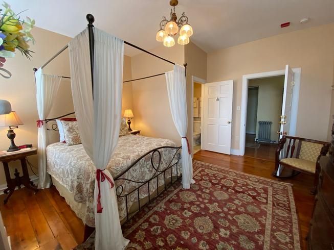 A bedroom with a canopy bed and a rug