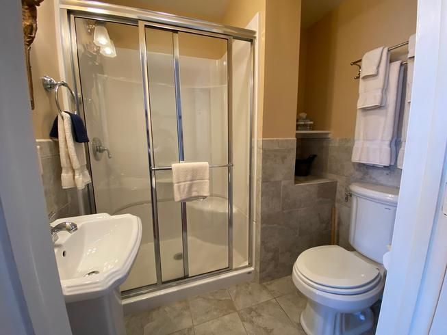 A bathroom with a toilet , sink and shower.