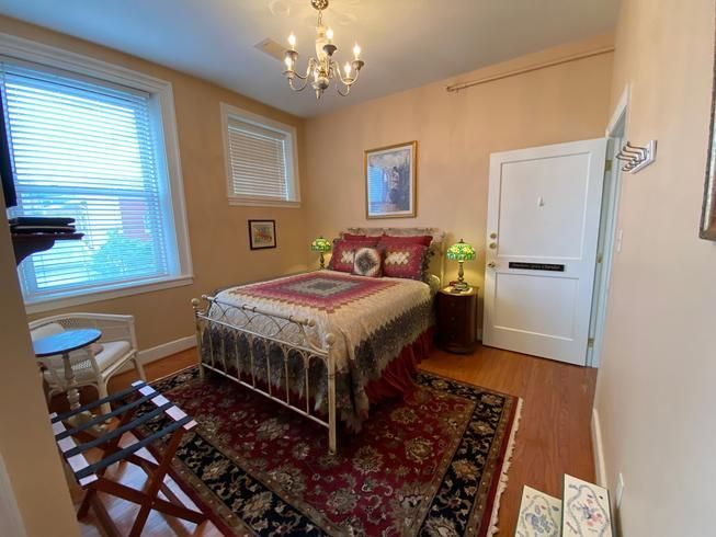 A bedroom with a bed , chair , table and rug.