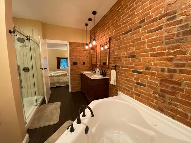 A bathroom with a brick wall and a bathtub.