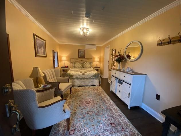 A bedroom with a bed , chairs , dresser and mirror