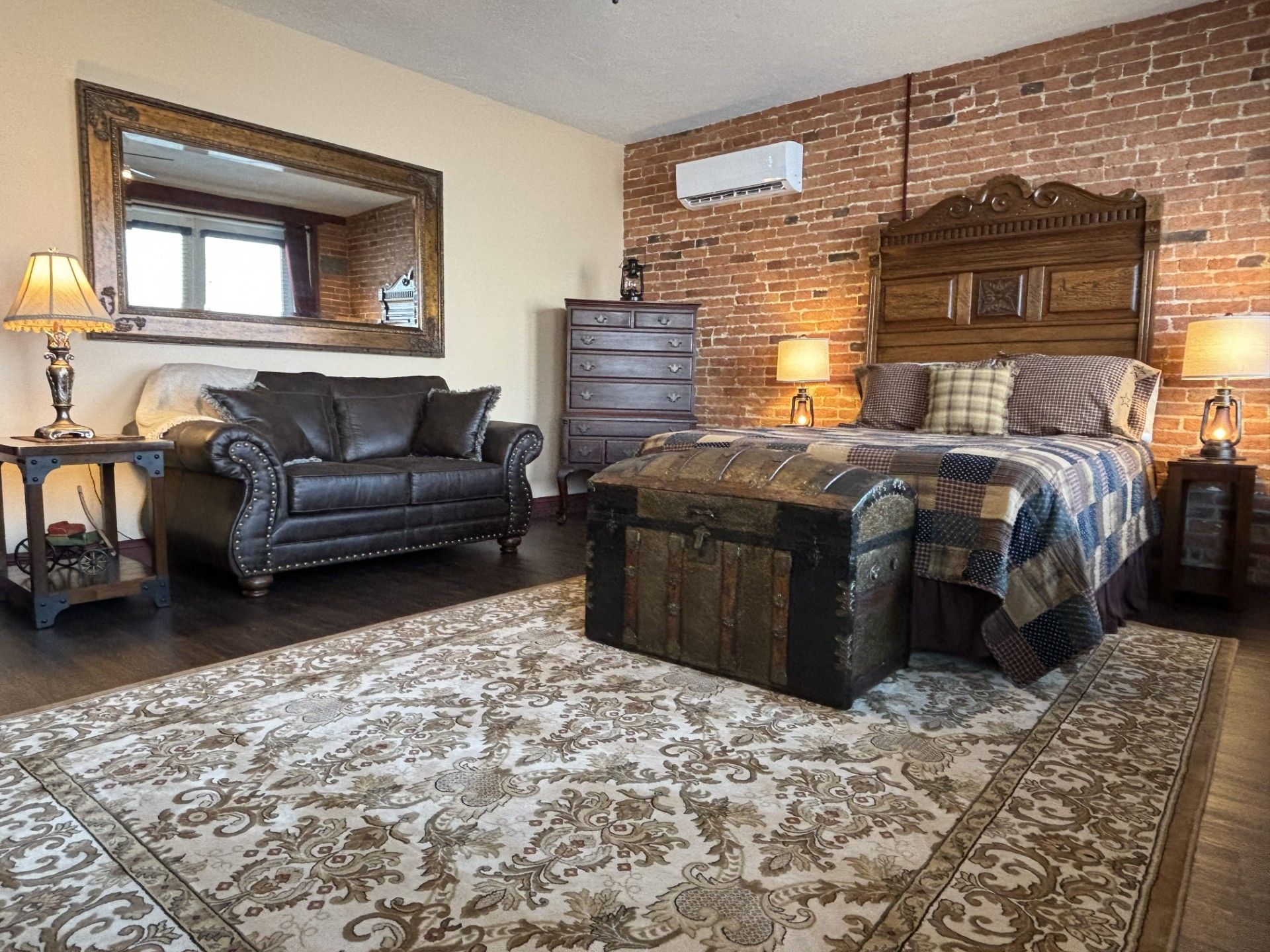 A bedroom with a bed , couch , dresser and mirror.