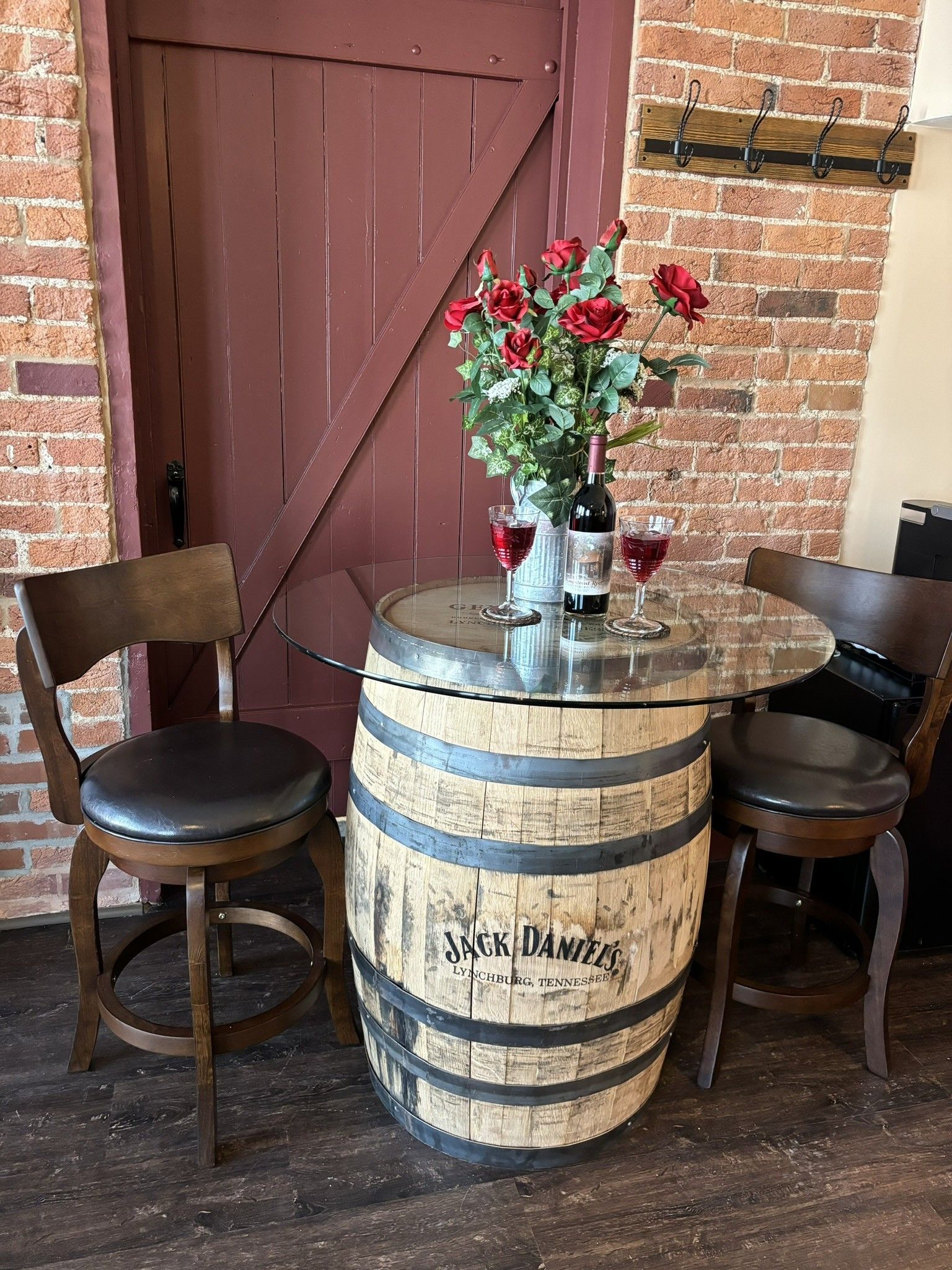 A wine barrel table with two chairs and a vase of flowers on it.