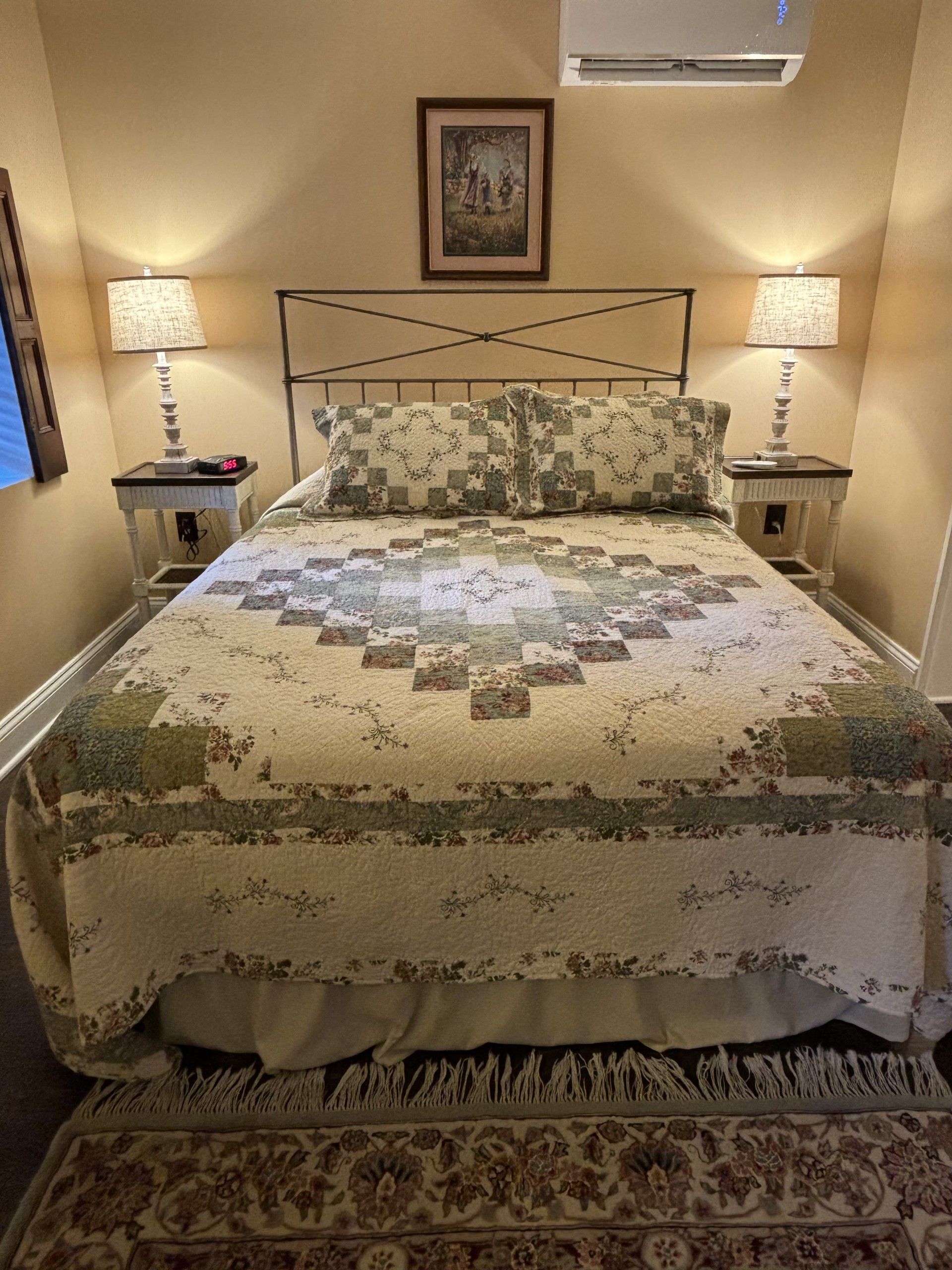 A bedroom with a bed , two lamps and a picture on the wall.