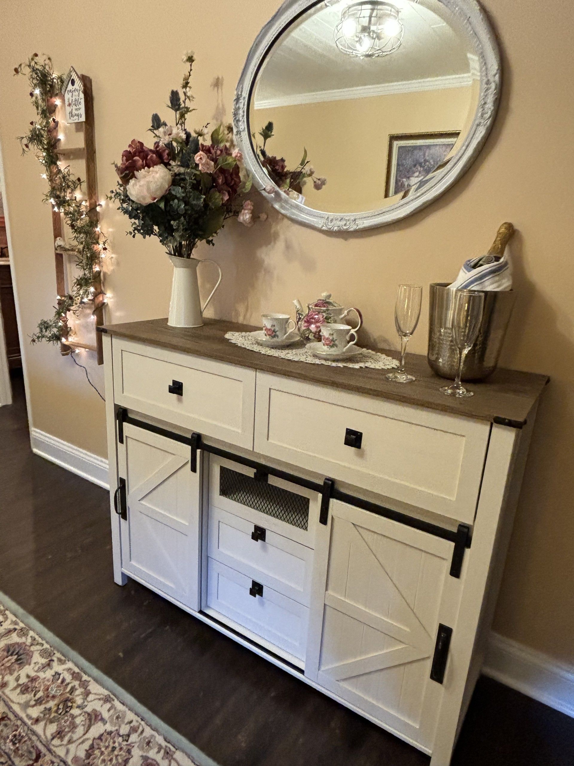 A white dresser with a mirror and flowers on top