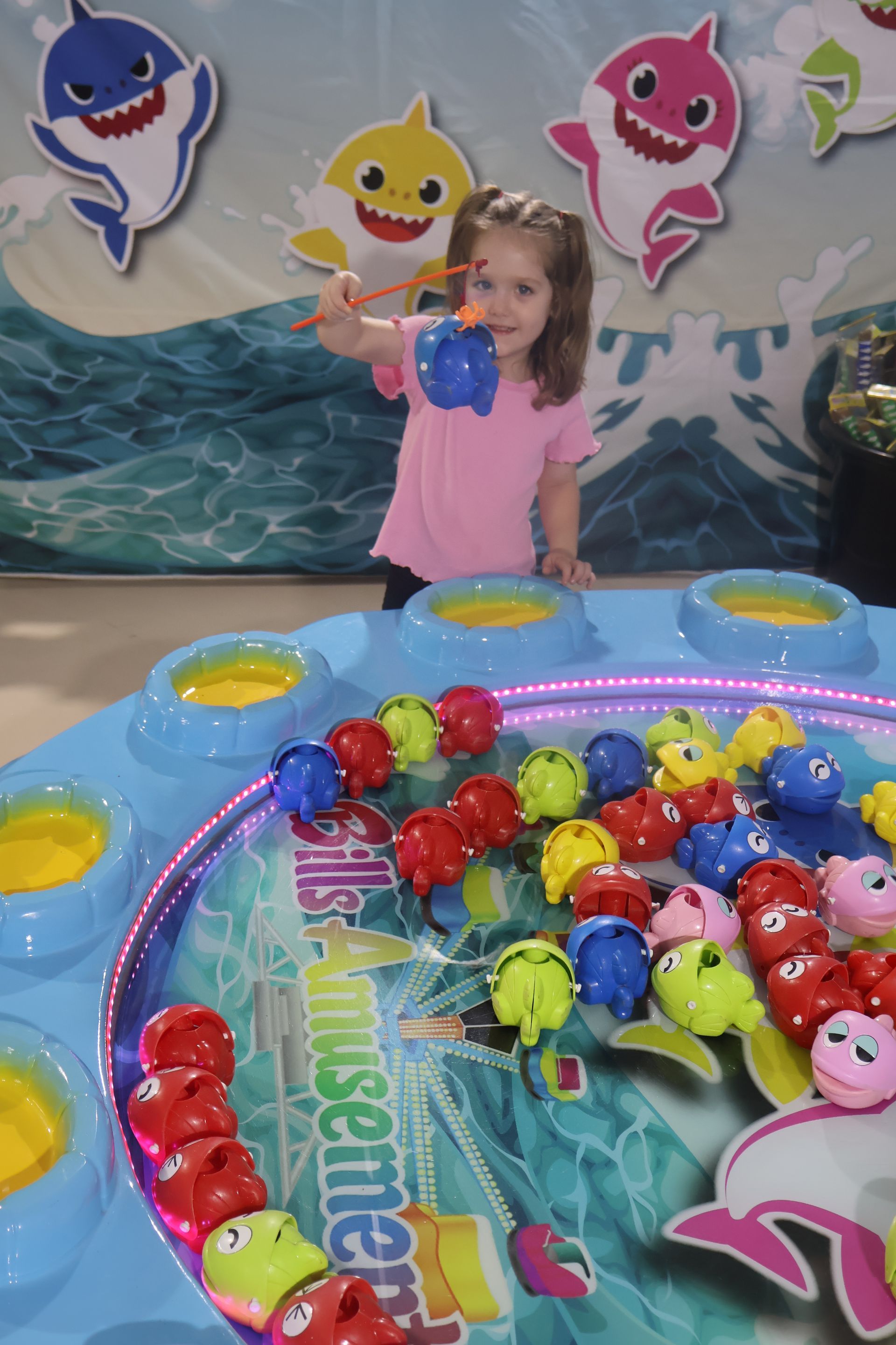 A little girl is playing a game with baby sharks on the wall behind her — Bills Amusements In Rockhampton, QLD
