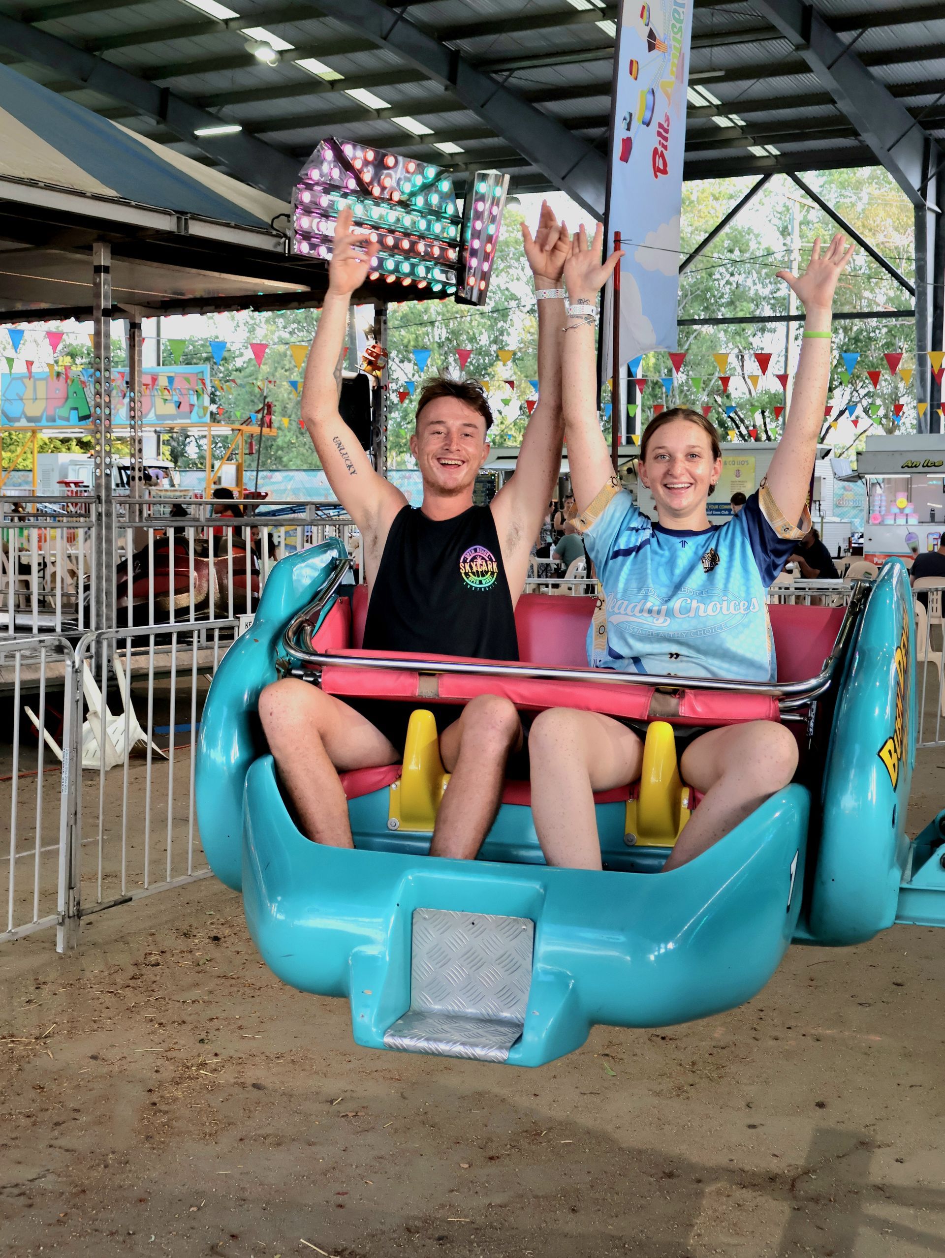 A Man And A Woman Are Riding A Roller Coaster With Their Arms In The Air — Bills Amusements In Rockhampton, QLD