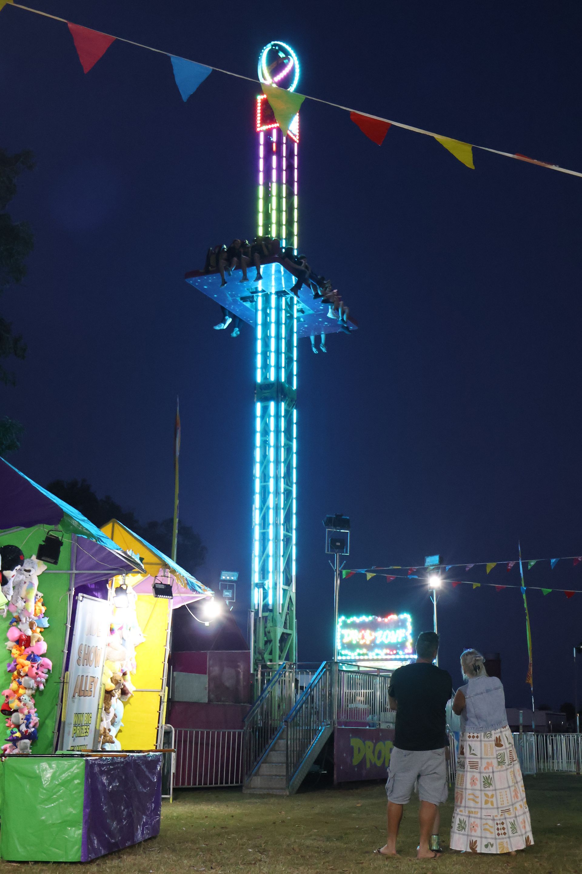 A Group Of People Are Riding A Ferris Wheel At Night — Bills Amusements In Rockhampton, QLD