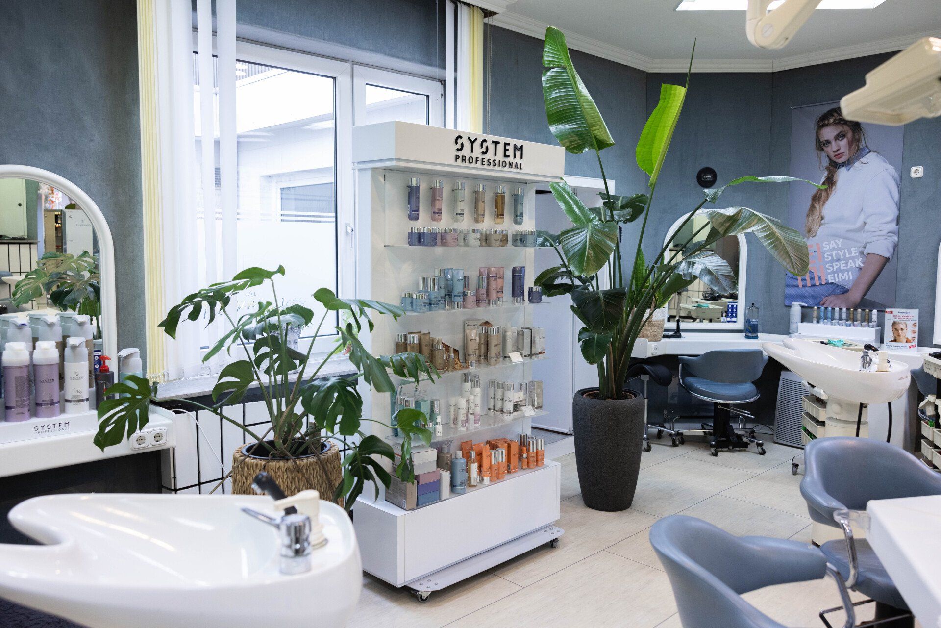 Innenraum eines Friseursalons mit Produktdisplays, Pflanzen, Waschbecken und Friseurstühlen.
