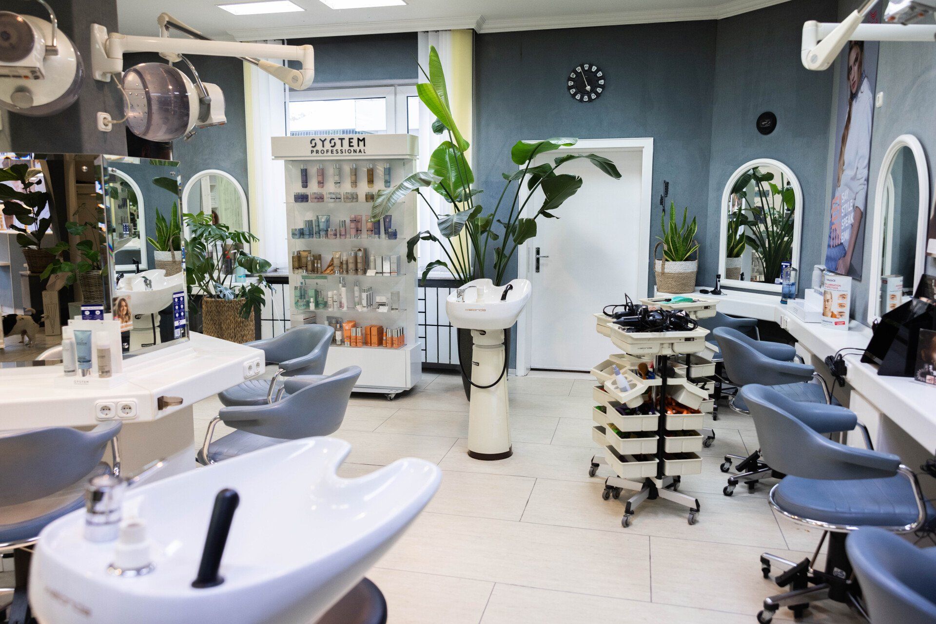 Inneneinrichtung eines Friseursalons mit Stationen, Spiegeln, Produkten und Pflanzen.