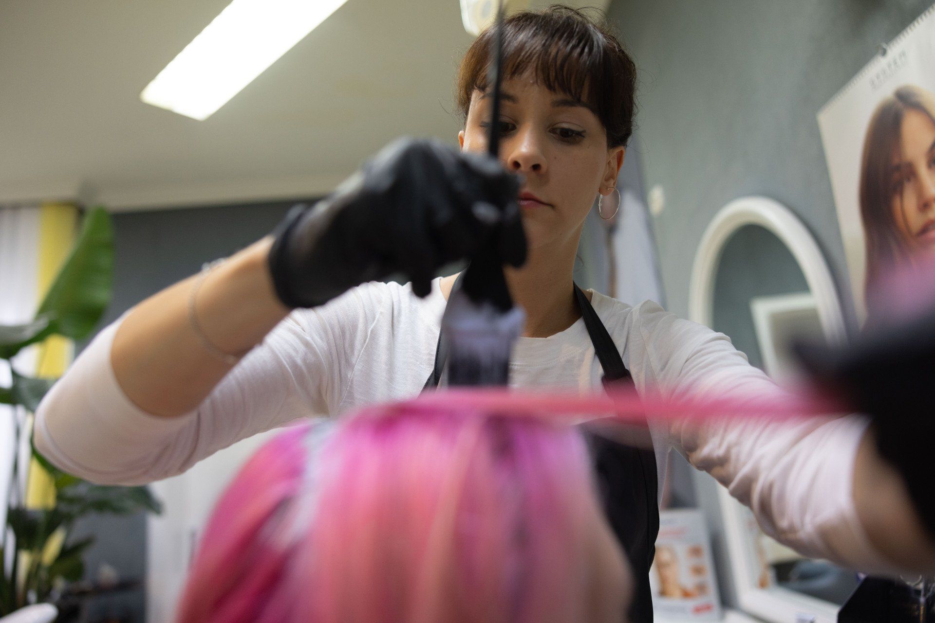 Friseur trägt rosa Farbe auf das Haar auf.