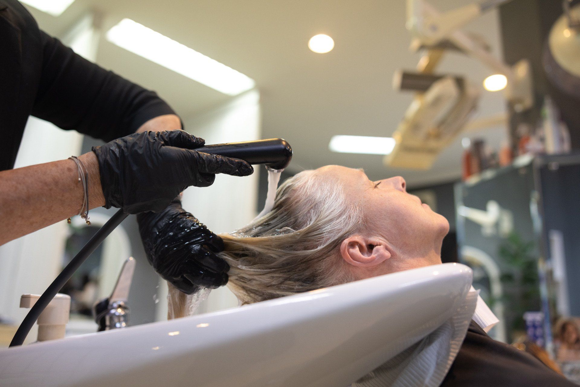 Person lässt sich in einem Salon die Haare waschen; 
