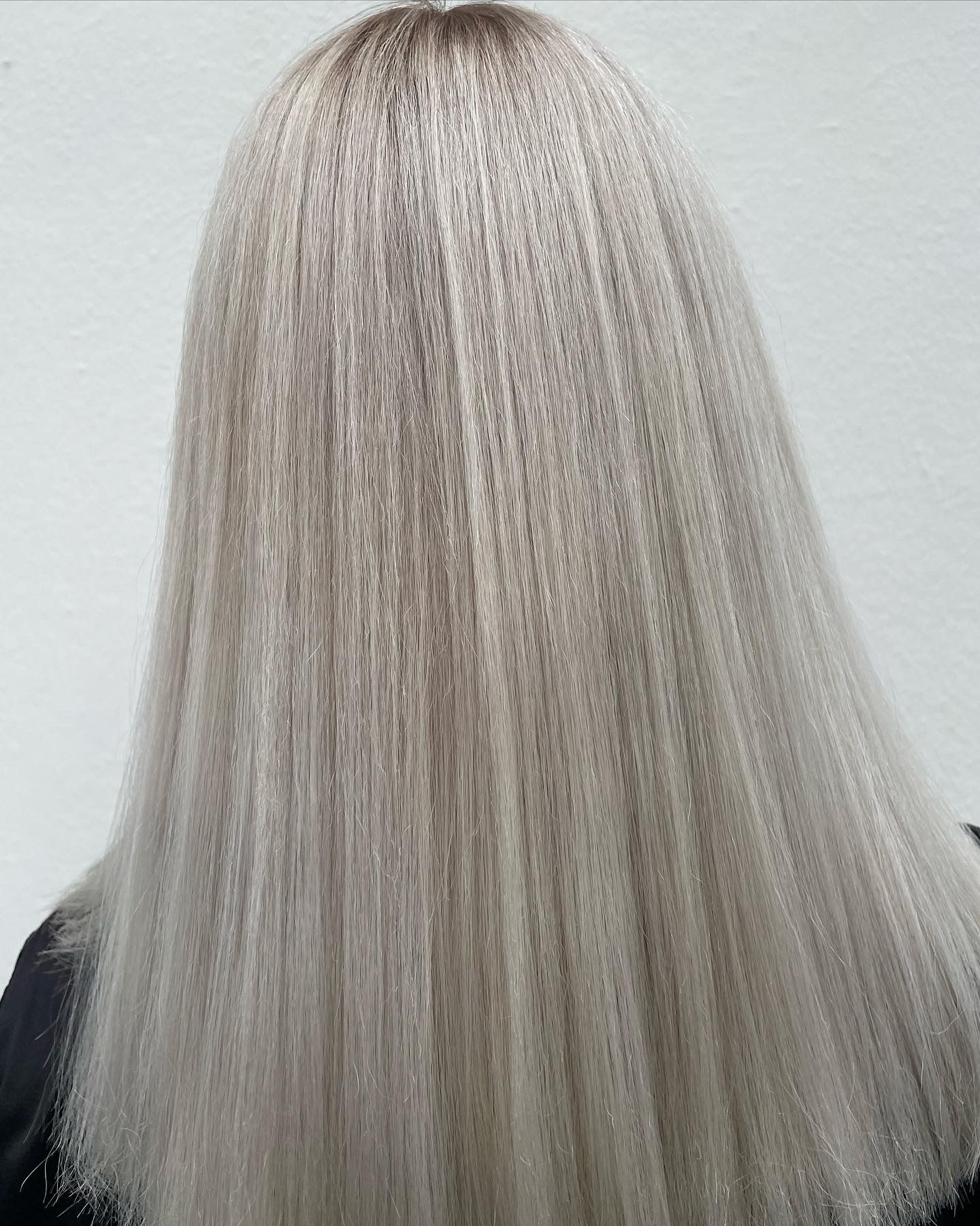 Person mit langem, glattem, hellem Haar, Rückansicht. Das Haar wirkt strukturiert mit dunkleren Wurzeln.