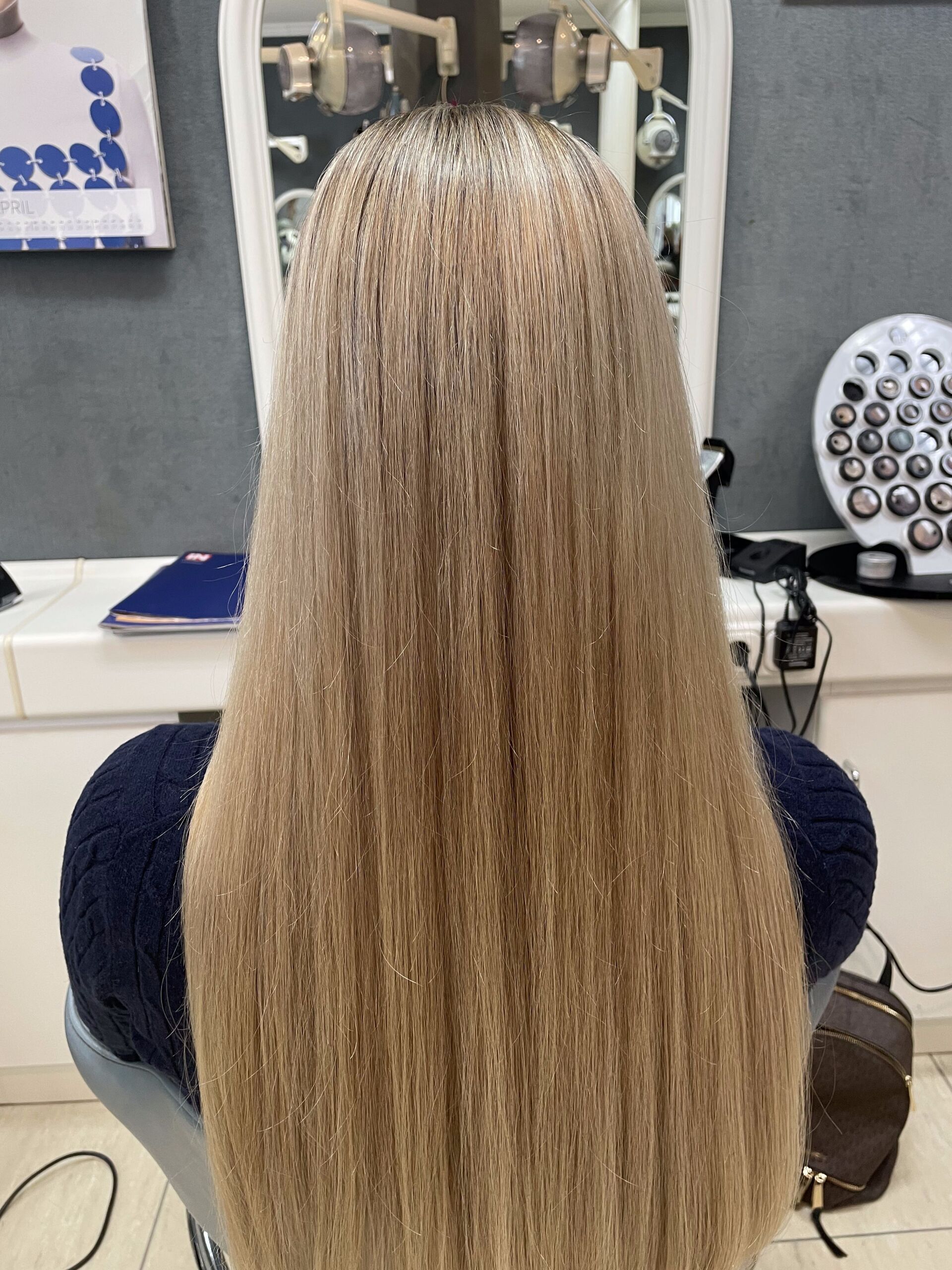 Frau mit langem, glattem, hellbraunem Haar in einem Salon, das Haar fällt ihr über den Rücken.