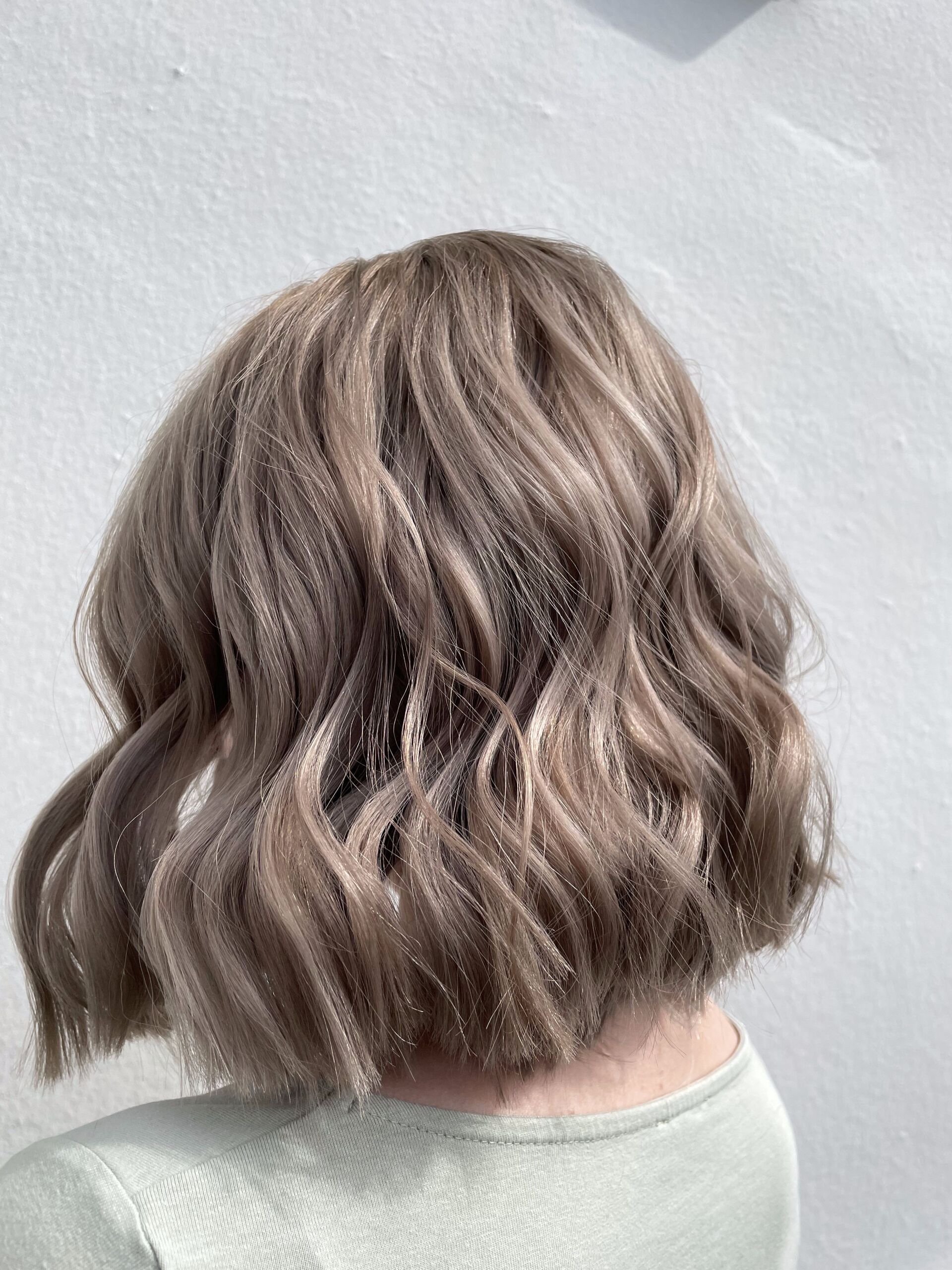 Schulterlanges, welliges graues Haar vor weißem Hintergrund.