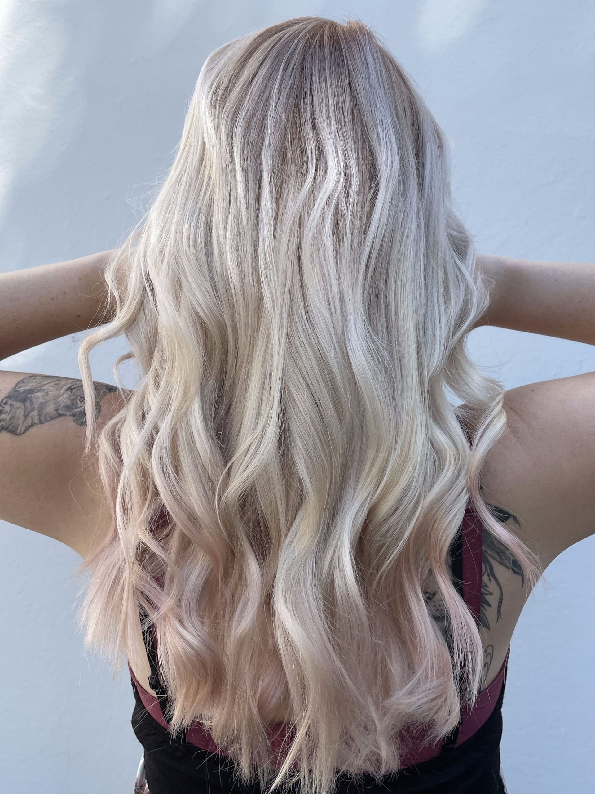 Frau mit langen, welligen blonden Haaren, die die Arme hochhält.