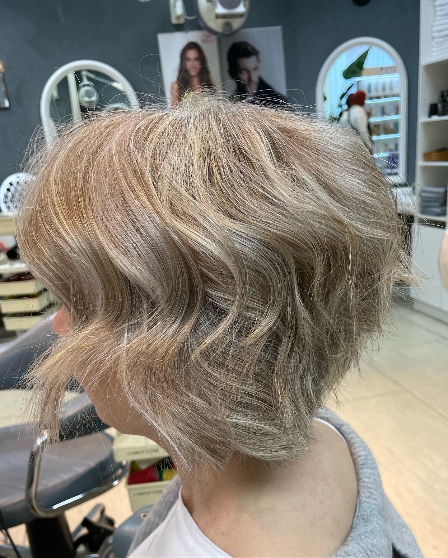 Blonde, wellige Bobfrisur an einer Person in einem Salon.