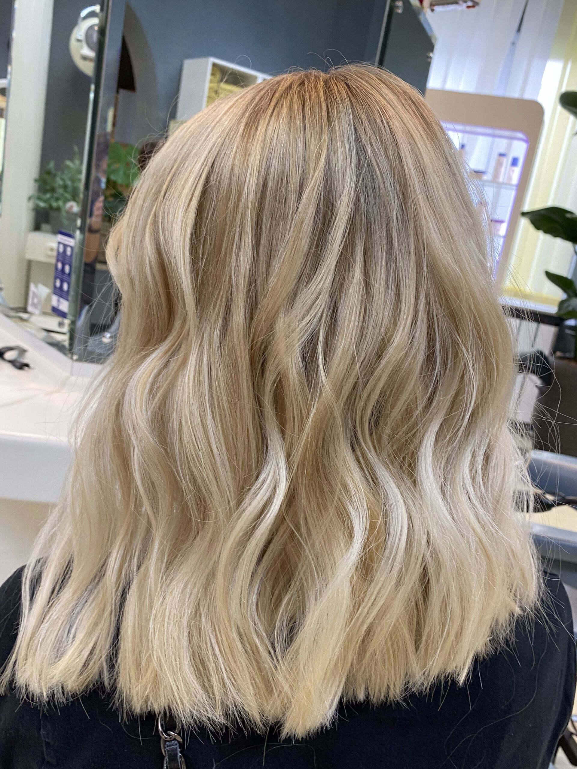 Blondes, welliges, schulterlanges Haar in einem Salon.