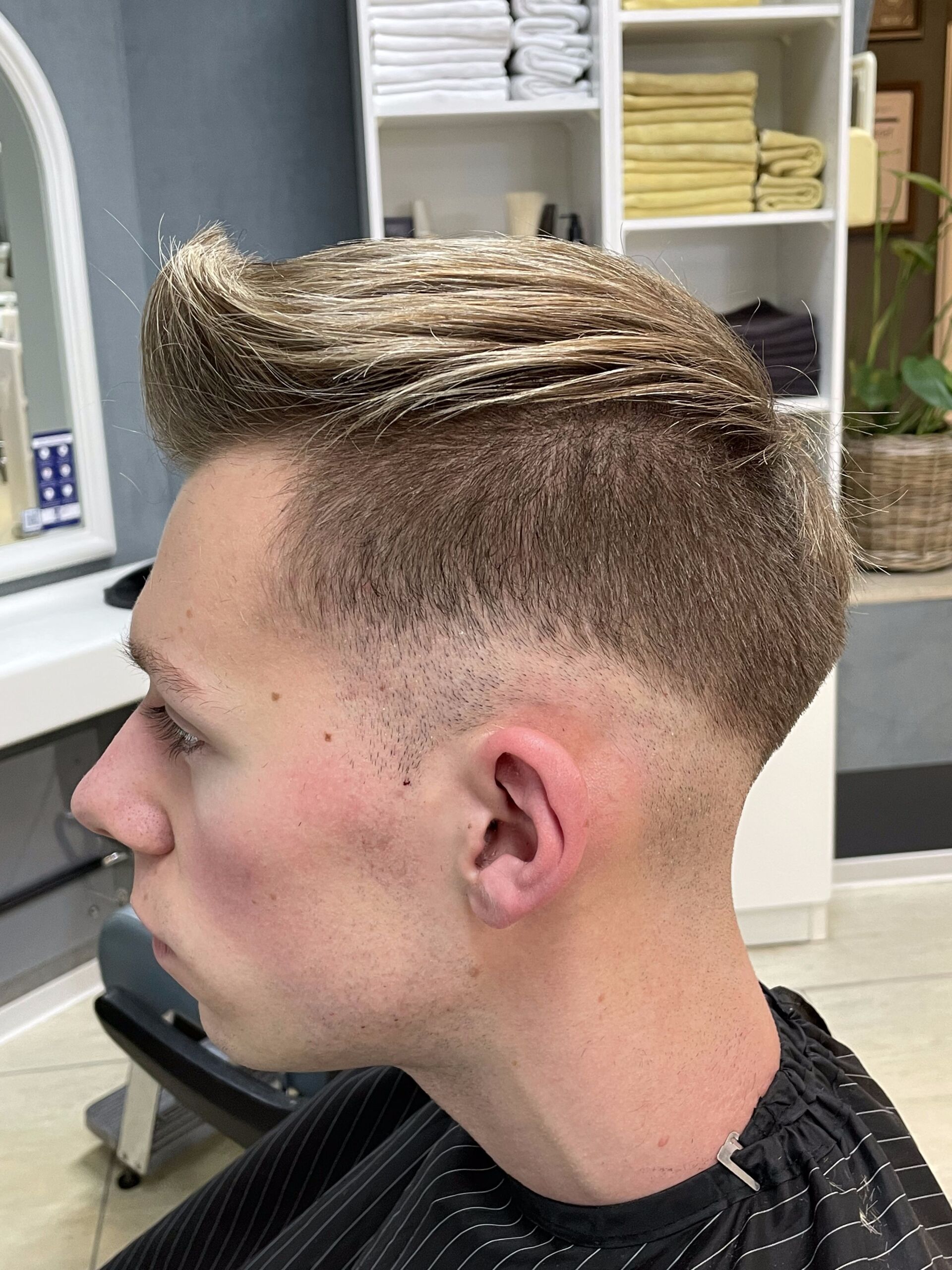Mann mit Fade-Haarschnitt, Profilansicht in einem Salon.