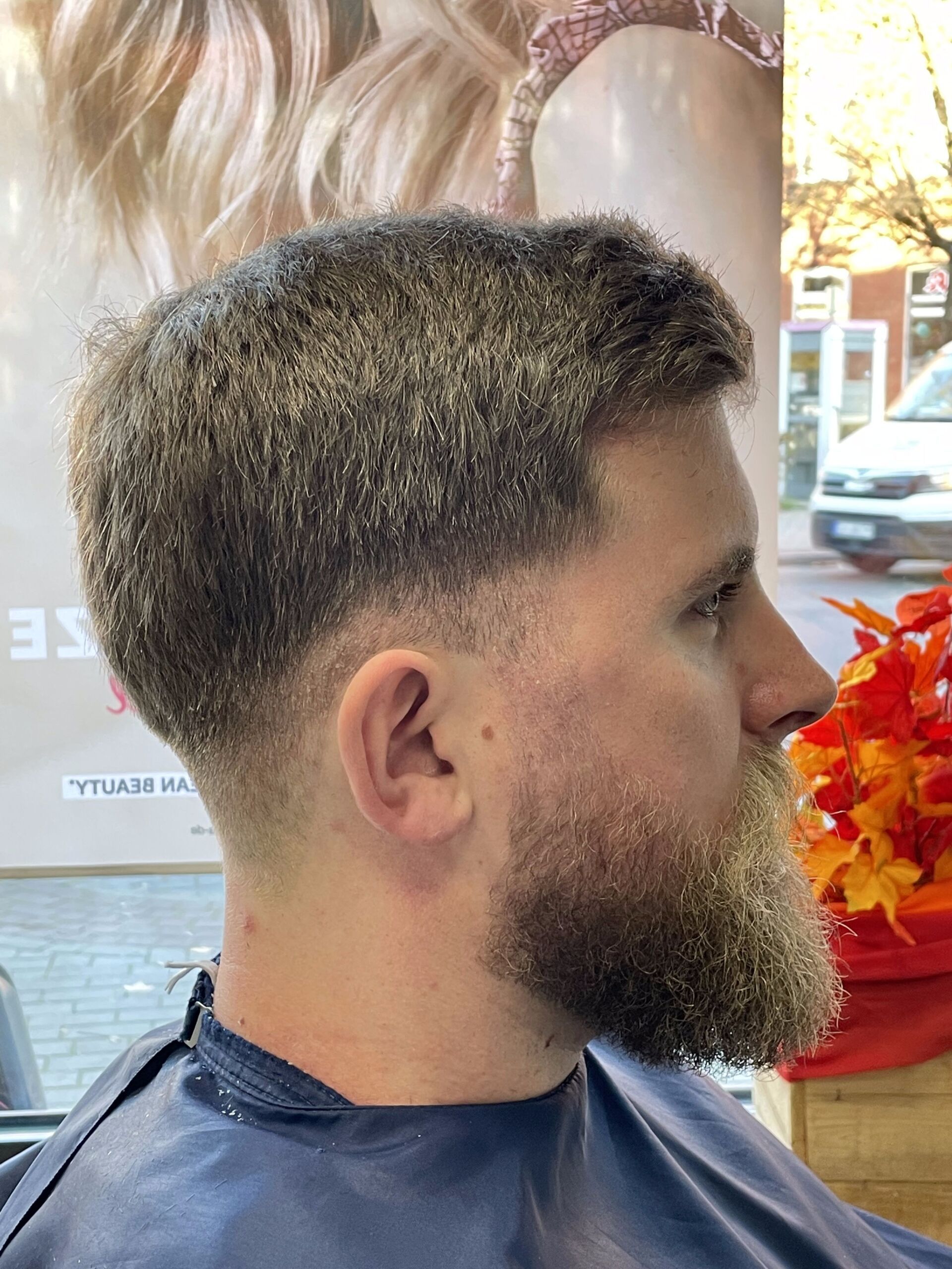 Mann mit Bart und verblasstem Haarschnitt in einem Salon. Dunkles Haar mit verblassten Seiten.