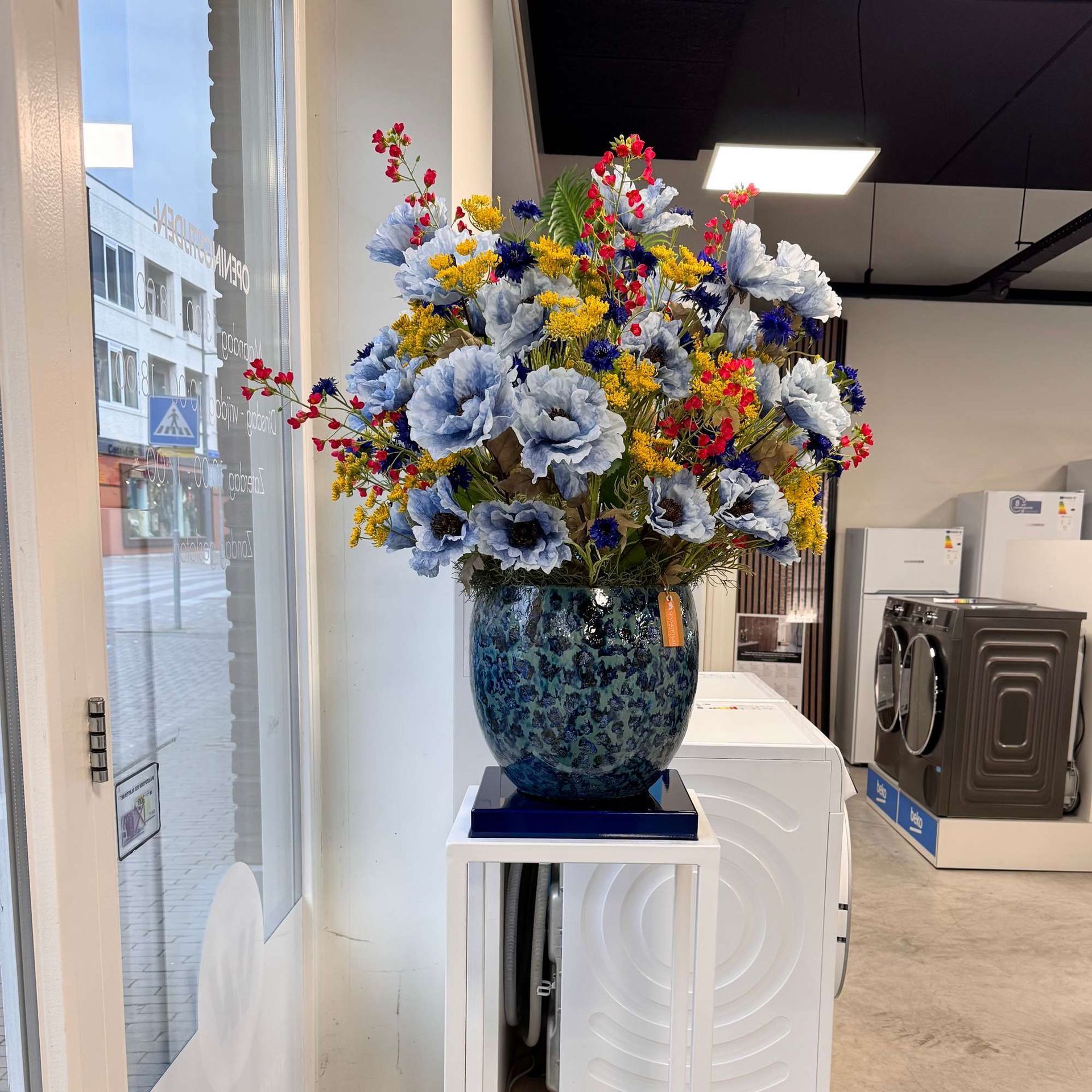 Een vaas gevuld met blauwe en gele bloemen staat op een tafel