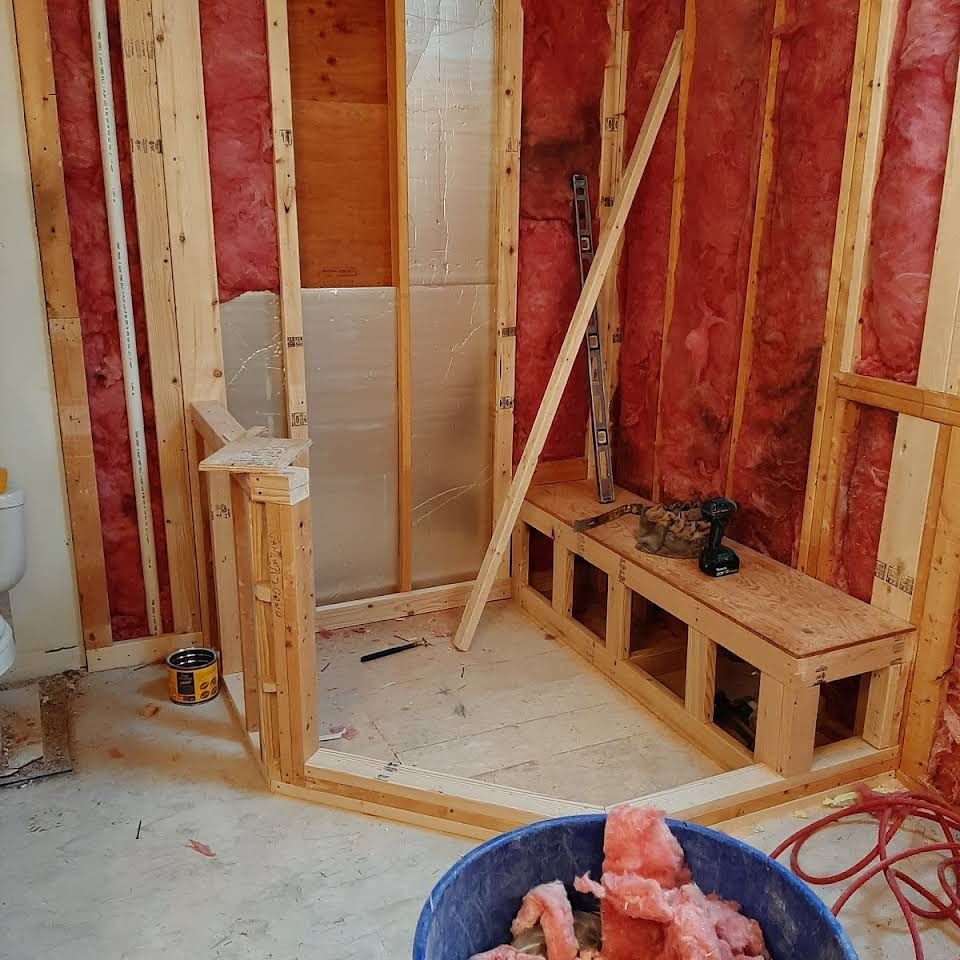 A bathroom under construction with a bucket of insulation on the floor