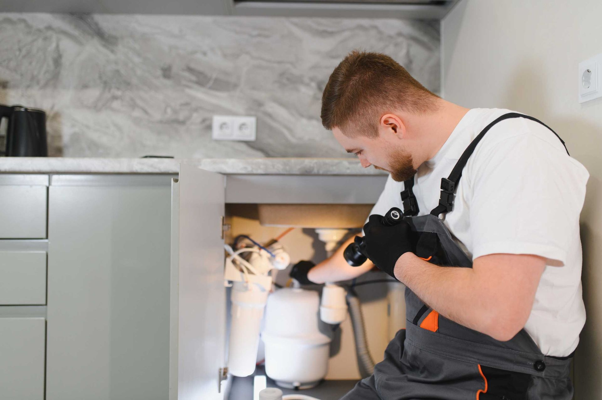 A plumber inspecting pipes in a residential home.