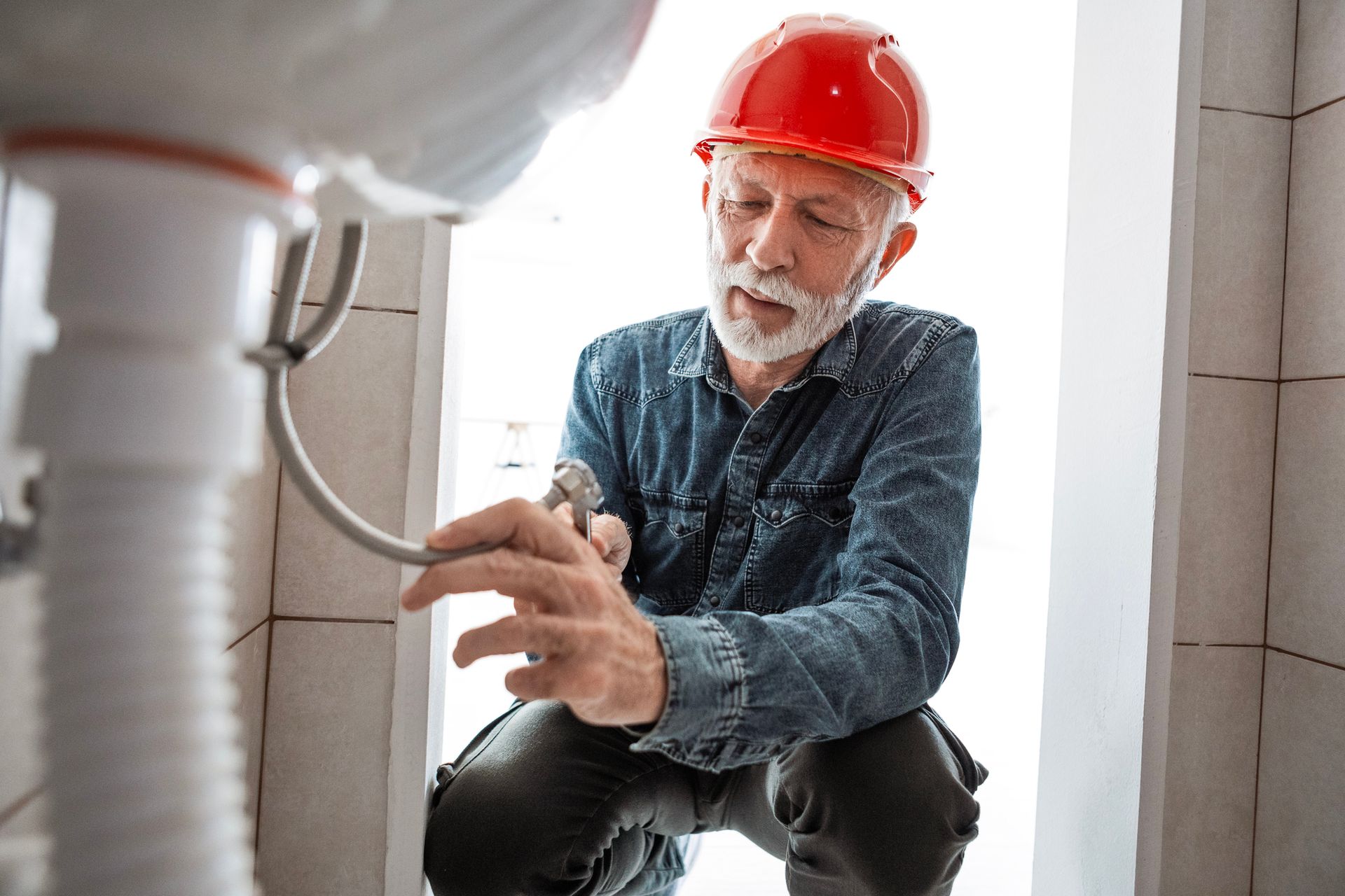Plumber repairing damaged sink pipe with tools.