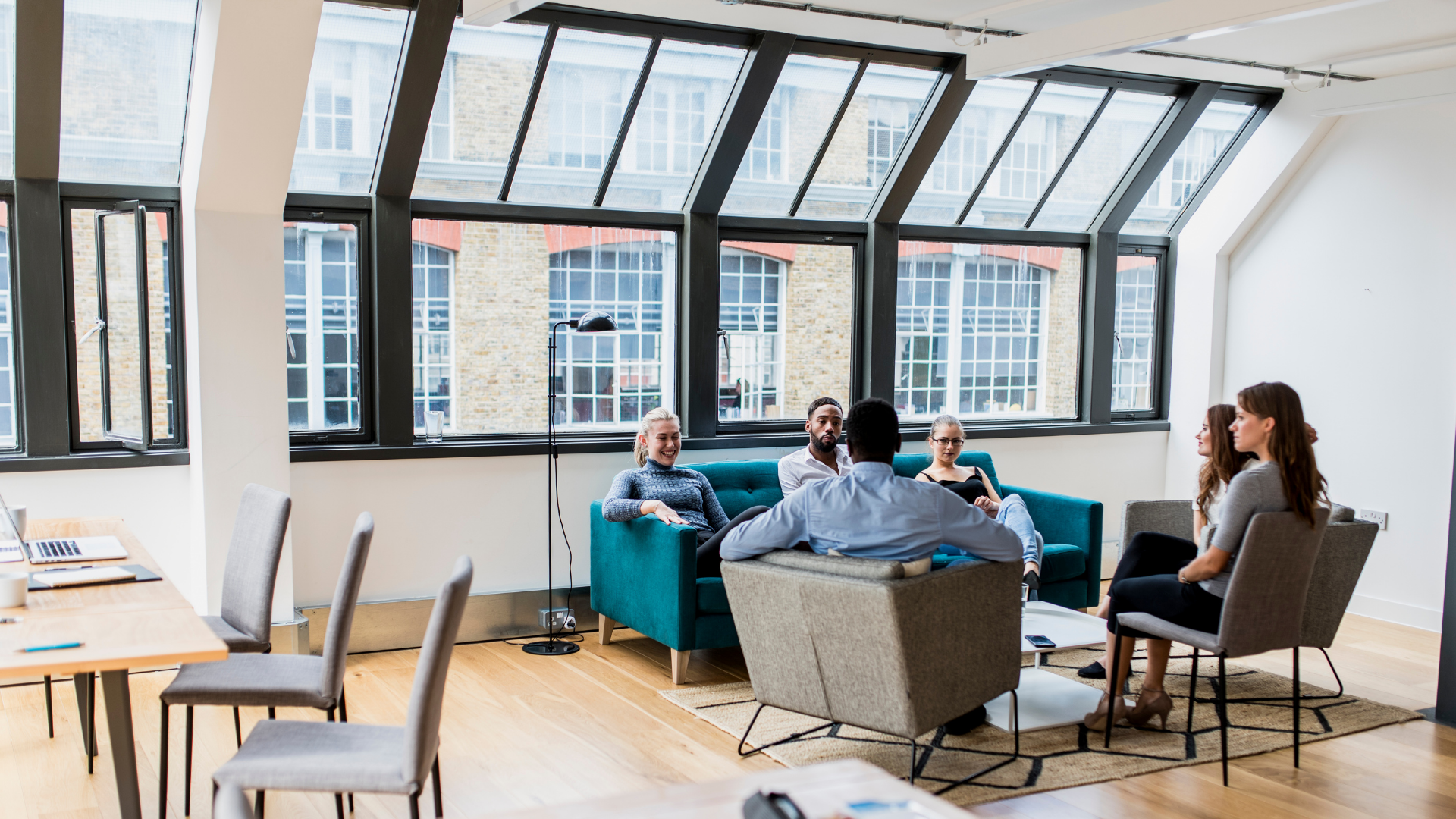 A group of people are sitting around a couch in a living room.