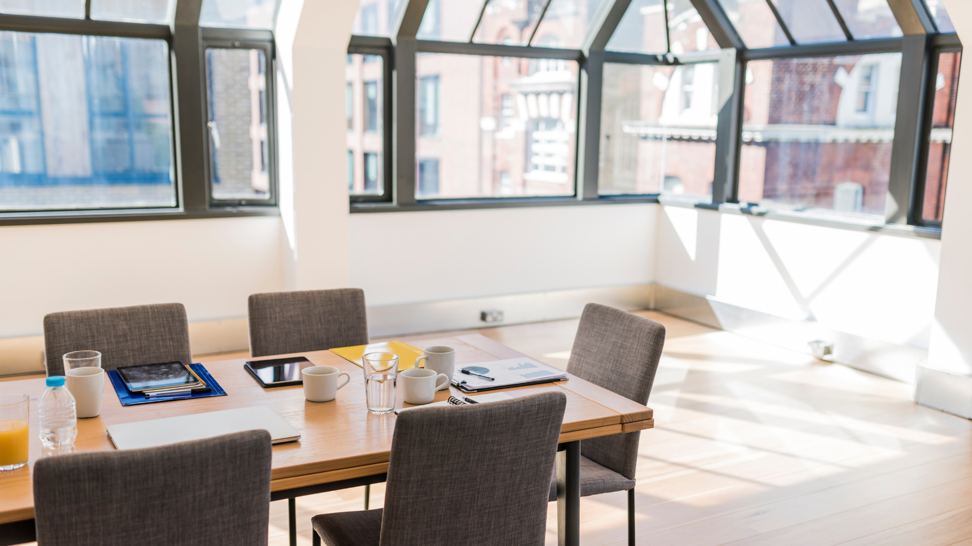 A conference room with a table and chairs and a lot of windows.