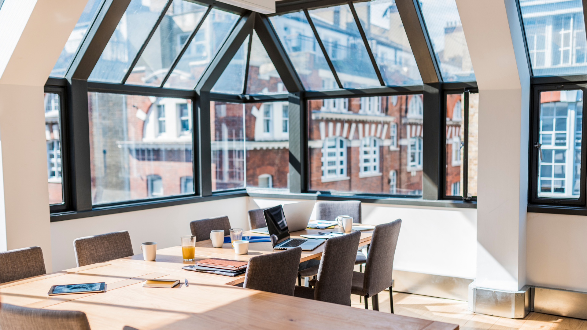 A conference room with a large table and chairs and lots of windows.
