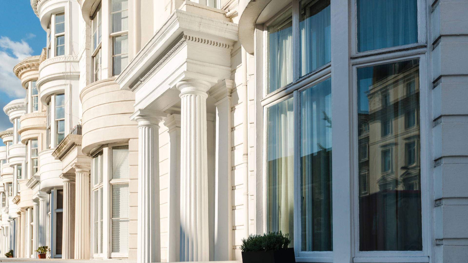 A row of white houses with a blue sky in the background.