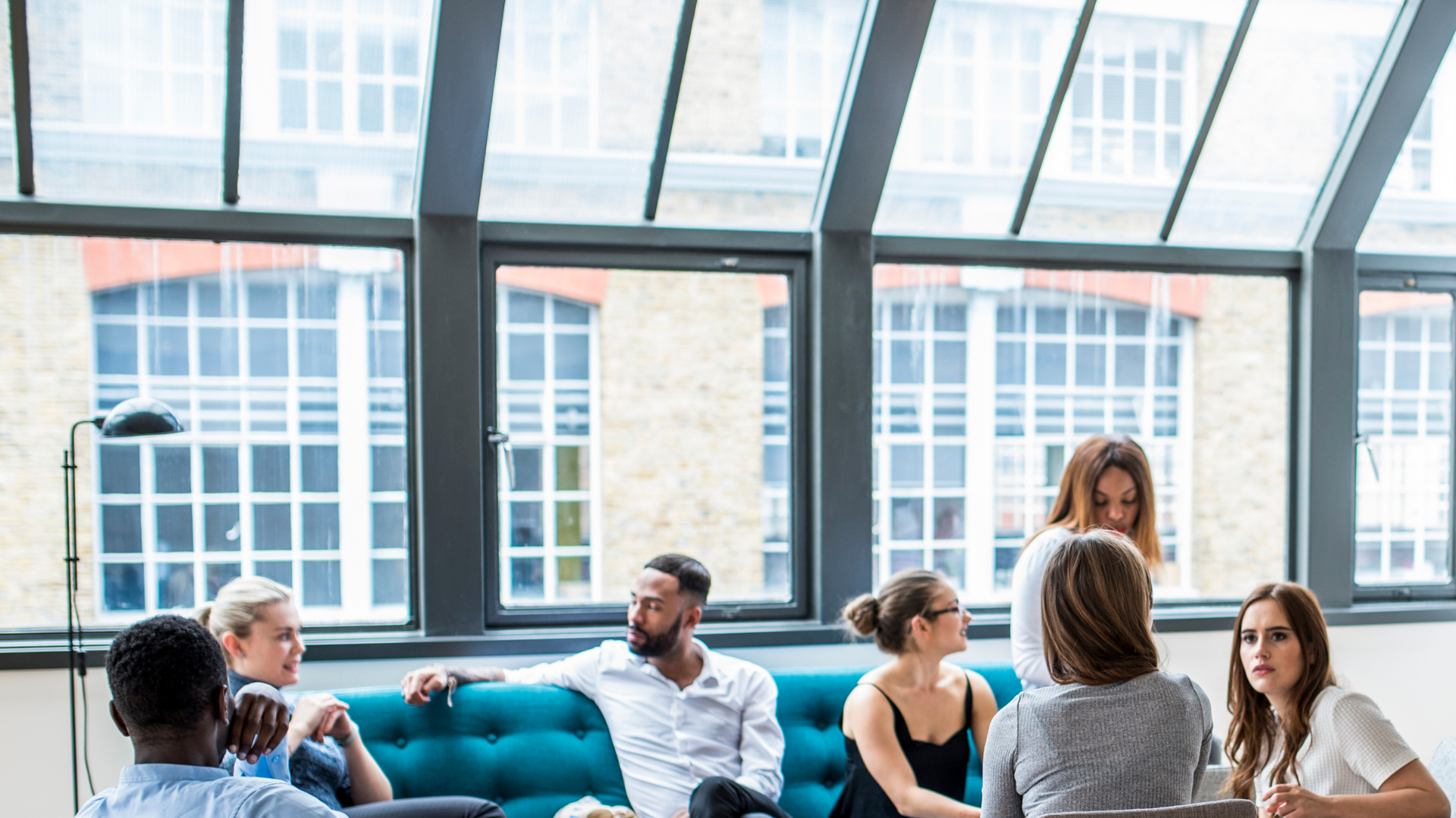 A group of people are sitting on a blue couch in a room.
