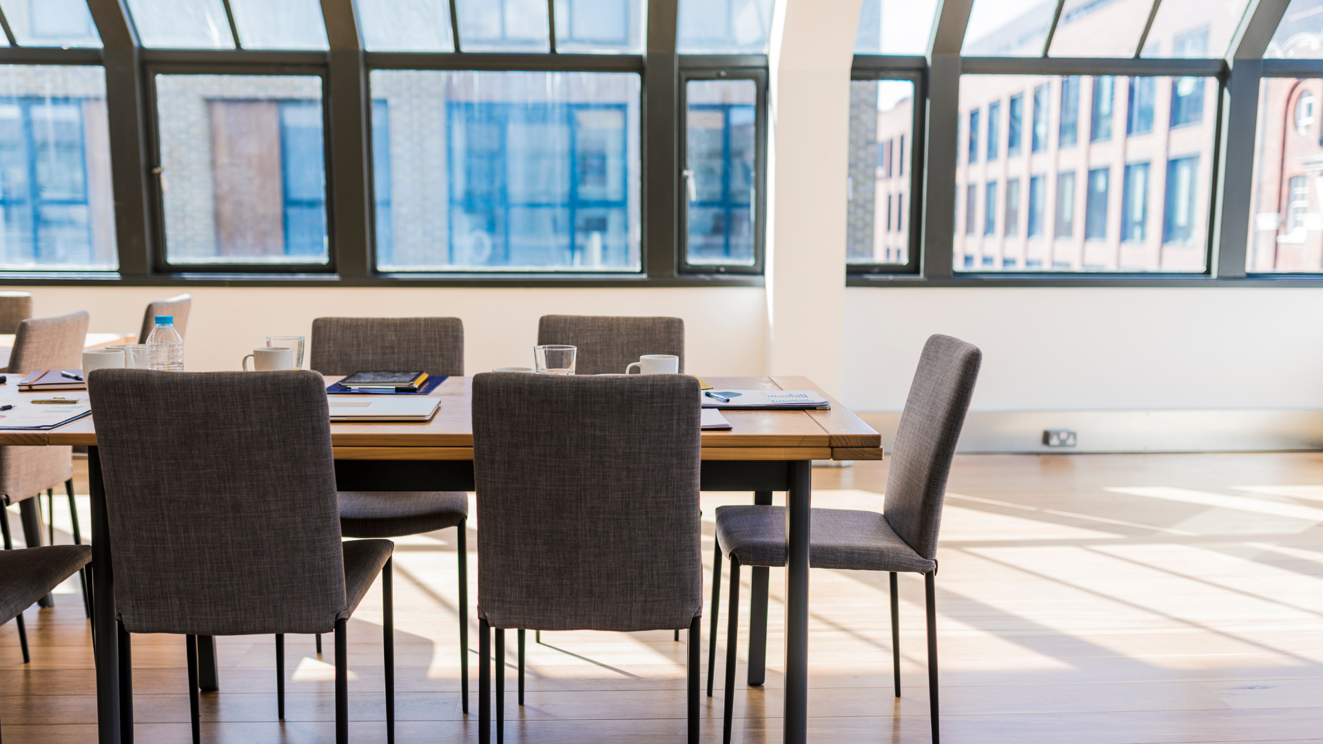 A dining room table and chairs in a large room with lots of windows.