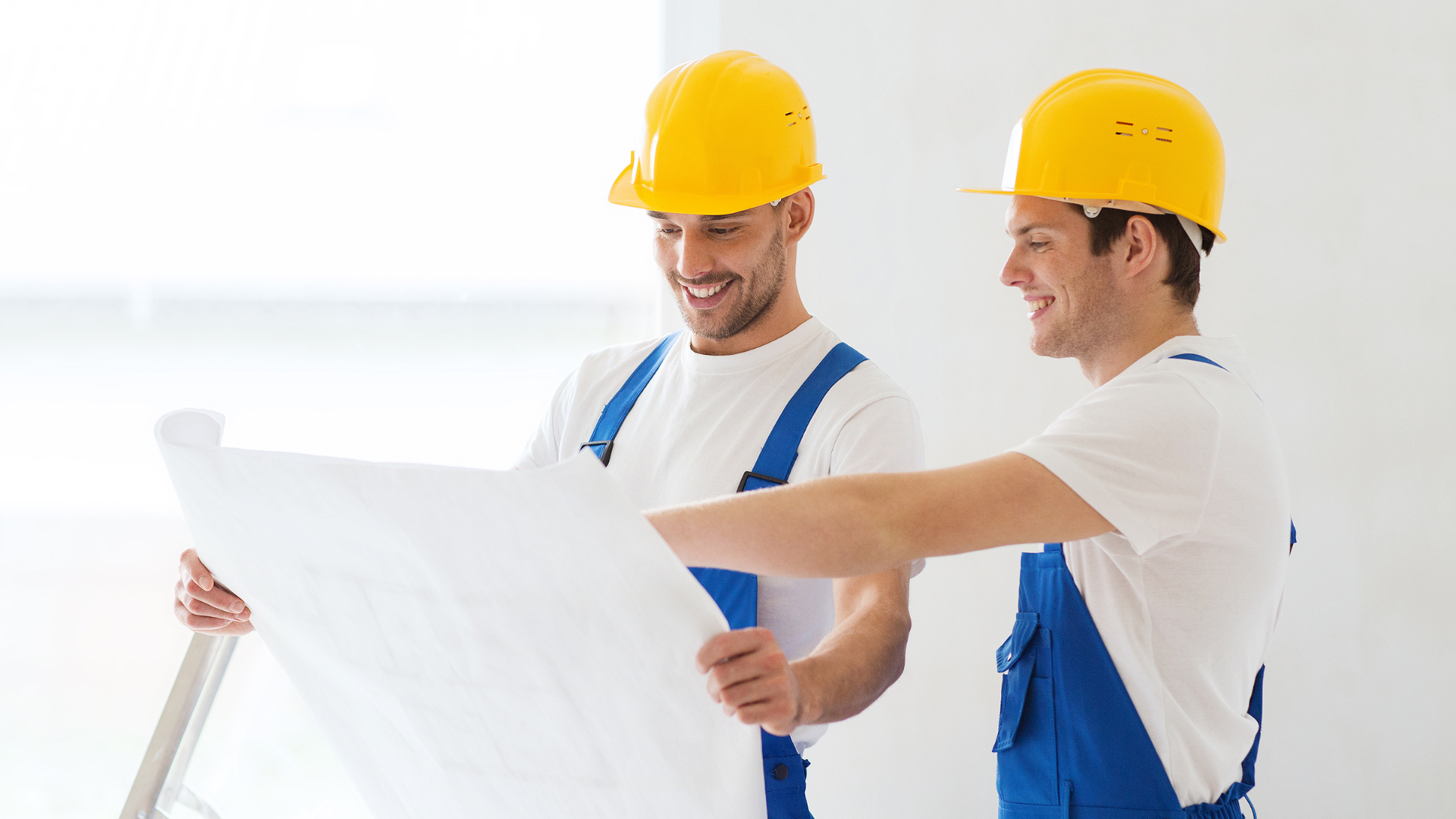 Two construction workers are looking at a blueprint together.