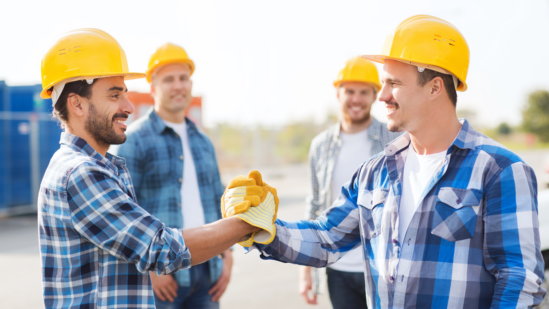 A group of construction workers are shaking hands on a construction site.