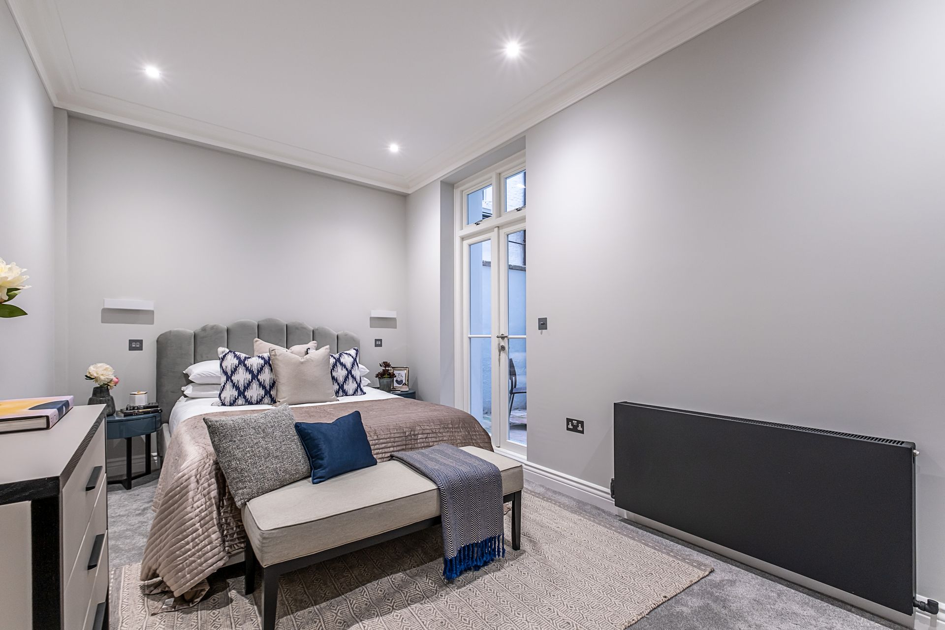 A bedroom with a large bed , a bench , and a radiator.