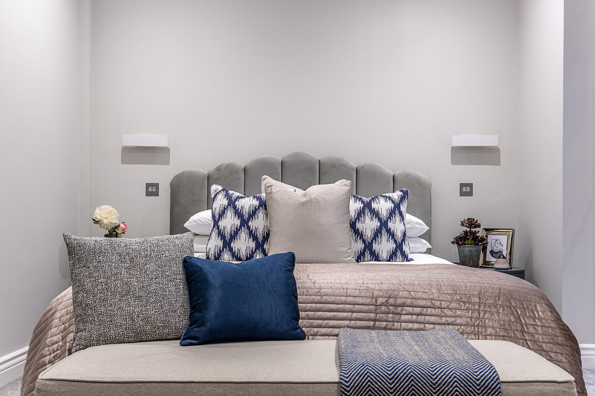 A bedroom with a bed , bench , and pillows on it.