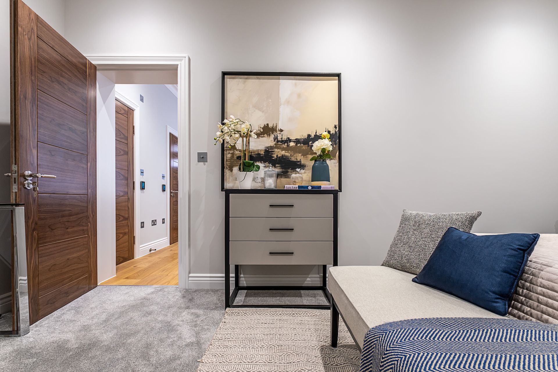 A living room with a couch , dresser , and a painting on the wall.