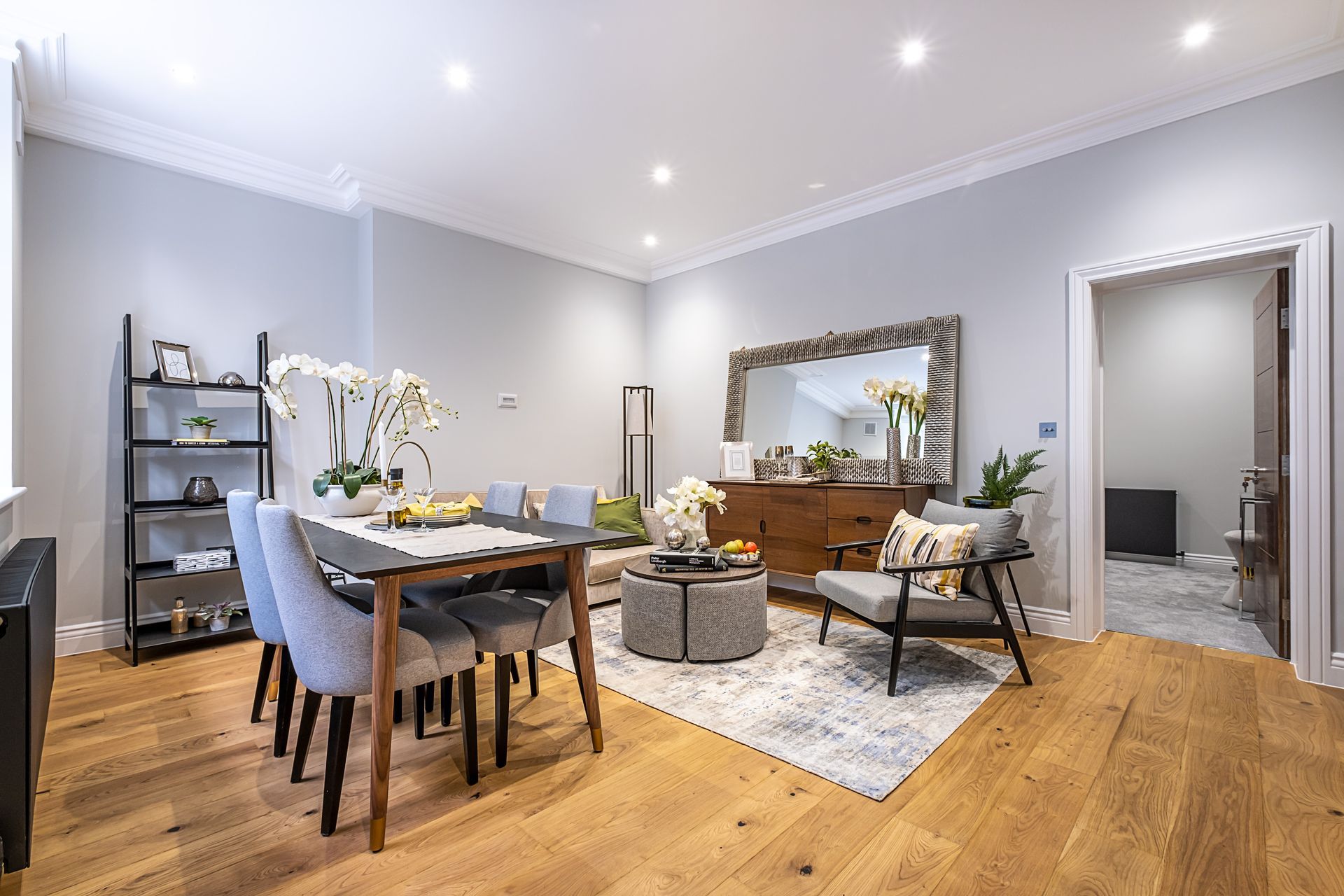A living room with a dining table and chairs and a mirror.