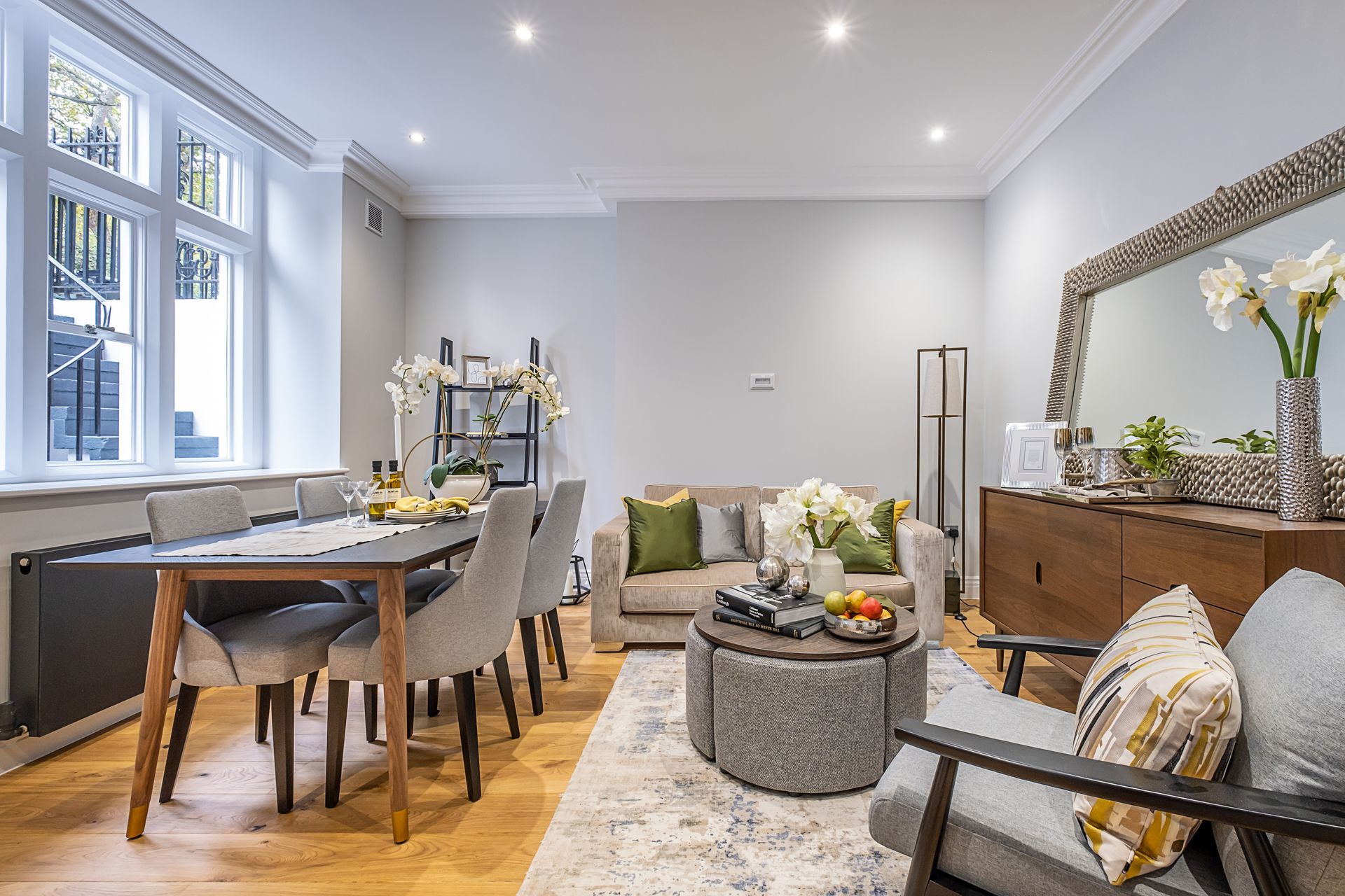 A living room with a couch , chairs , a table and a mirror.