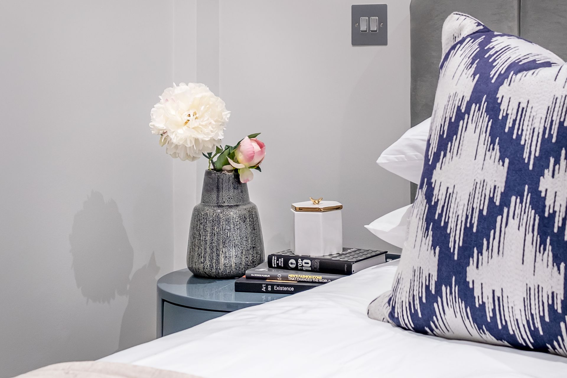 There is a vase of flowers on the nightstand next to the bed.